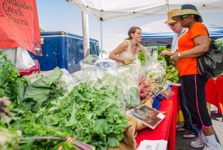 A vendor sells vegetables at a Richmond farmers' market